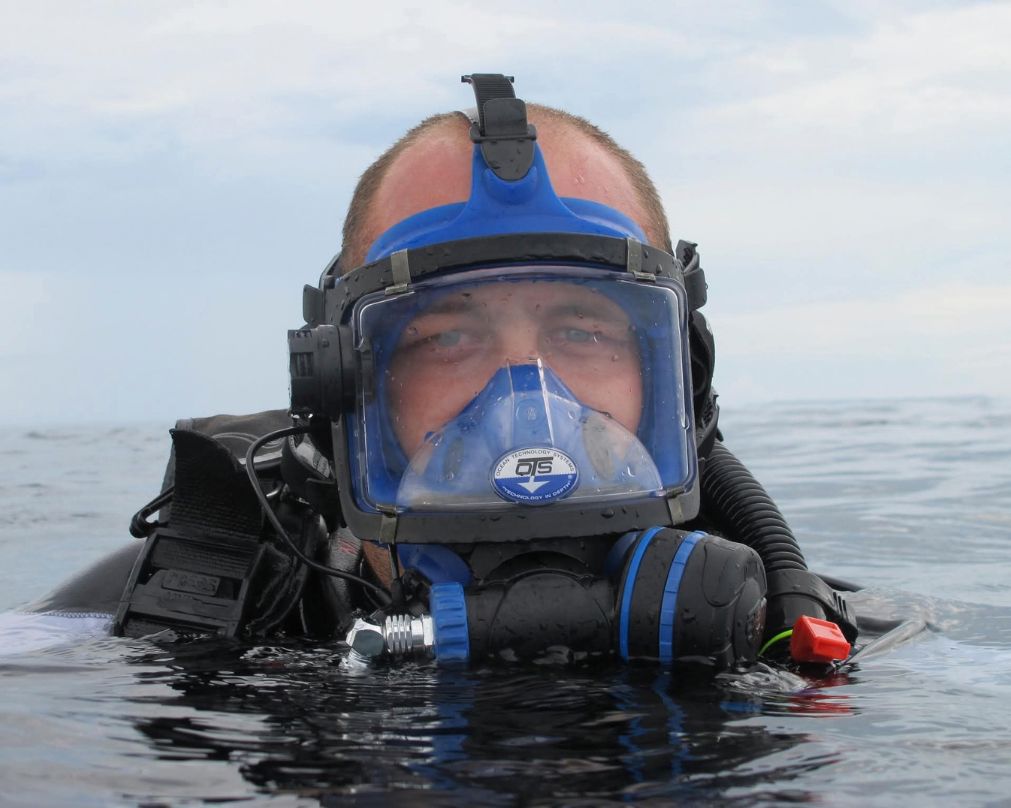 Man with blue eyes in the sea wearing diving gear and a mask